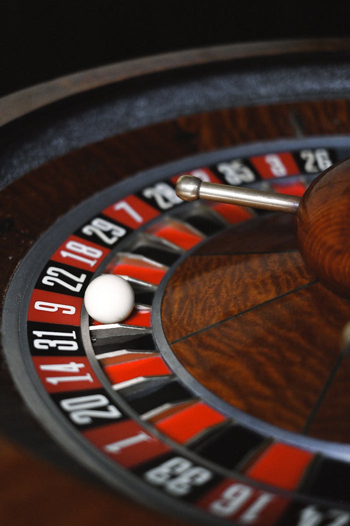 A close-up image of a spinning roulette wheel with a white ball in a casino setting.